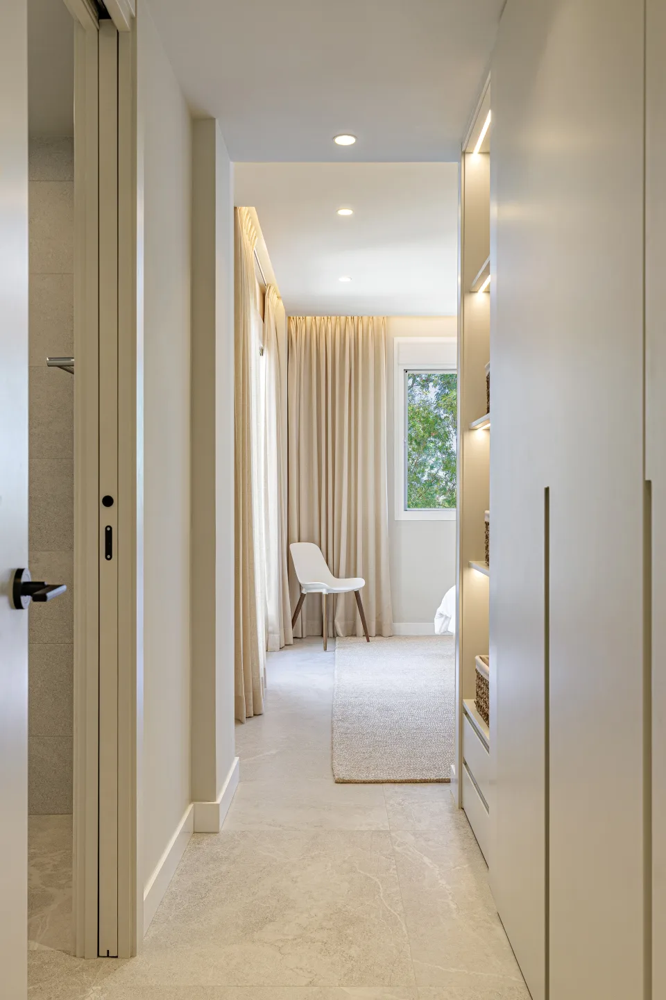Fotografía de alquiler vacacional de un pasillo iluminado con paredes claras, suelo de piedra y estanterías integradas en Nueva Andalucía | Penthouse en Urb. Fuente Aloha