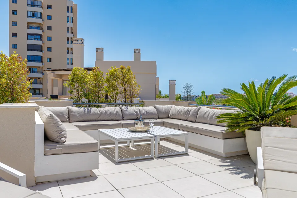 Fotografía de alquiler vacacional de un amplio ático con terraza, sofa amplio y plantas decorativas, ideal para relajarse en Nueva Andalucía