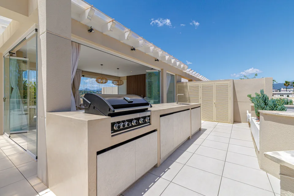 Vacation rental photograph of a spacious terrace with built-in barbecue, tables and views of the blue sky in Nueva Andalucía