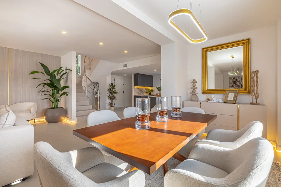 Interior design and architecture photograph of a stylish dining room with a wooden table, upholstered chairs in Cala de Mijas