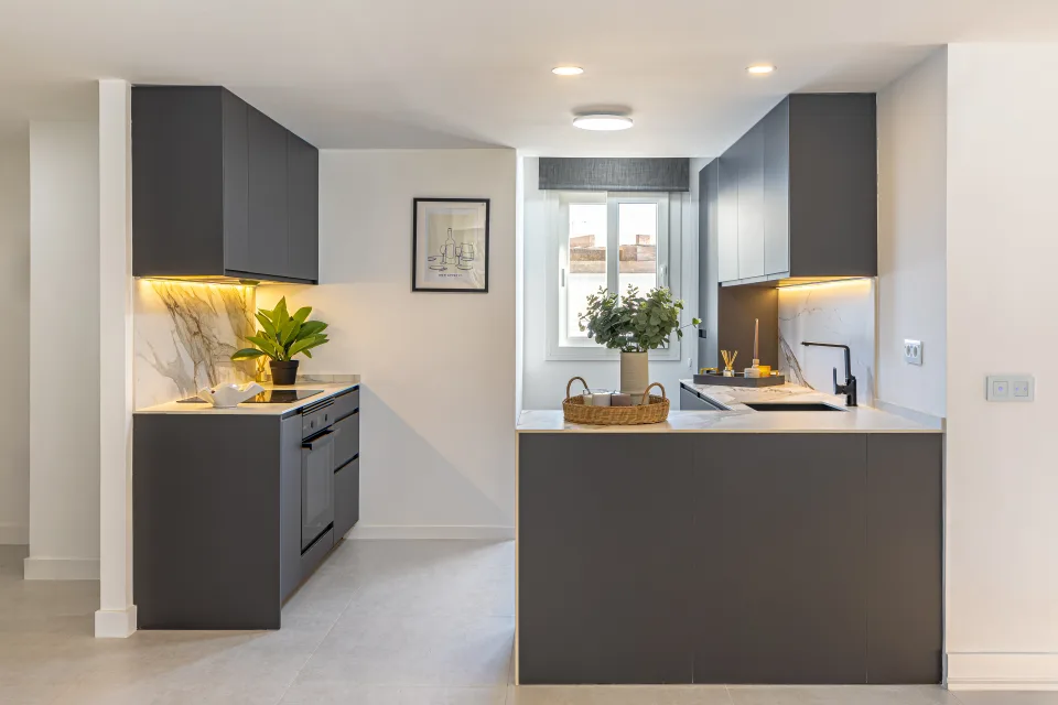 Interior design and architecture photograph of a modern kitchen with dark cabinetry, marble countertop and warm lighting in Cala de Mijas
