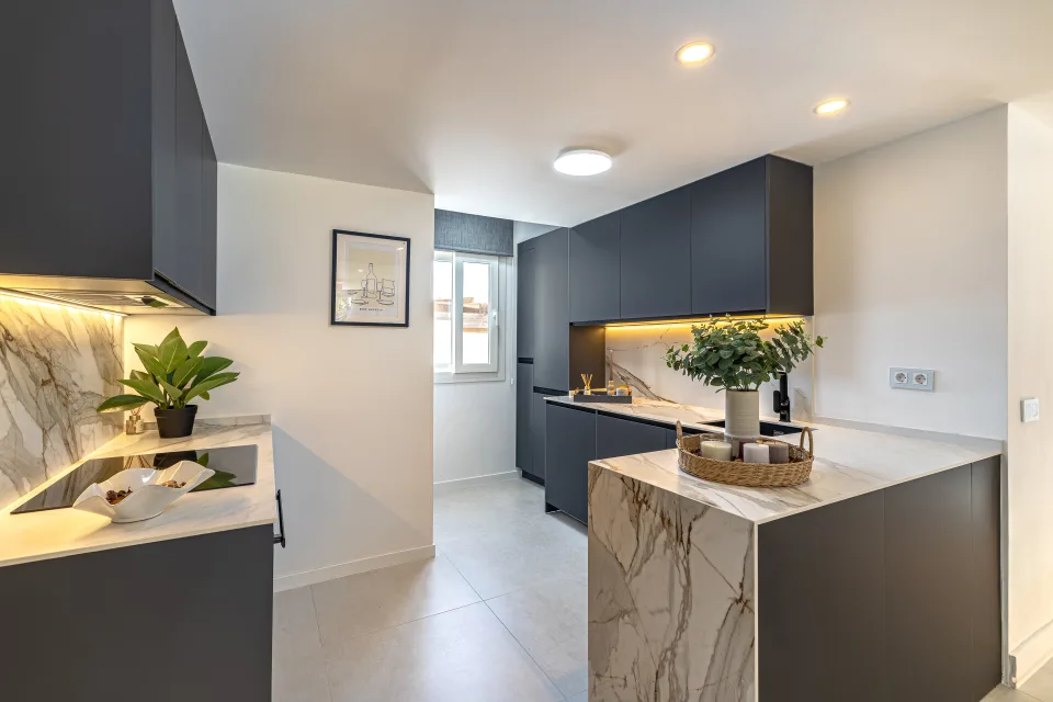 Interior design and architecture photograph of a modern and bright kitchen with marble countertops and dark-toned cabinetry in Cala de Mijas