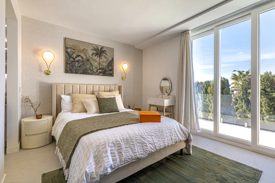 Interior design and architecture photograph of a cozy bedroom with a large bed, warm lighting and views to the exterior in Cala de Mijas