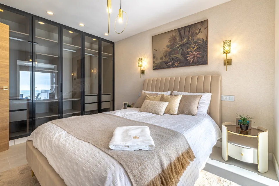Interior design and architecture photograph of a stylish bedroom with a upholstered double bed, glass wardrobe and modern decor in Cala de Mijas