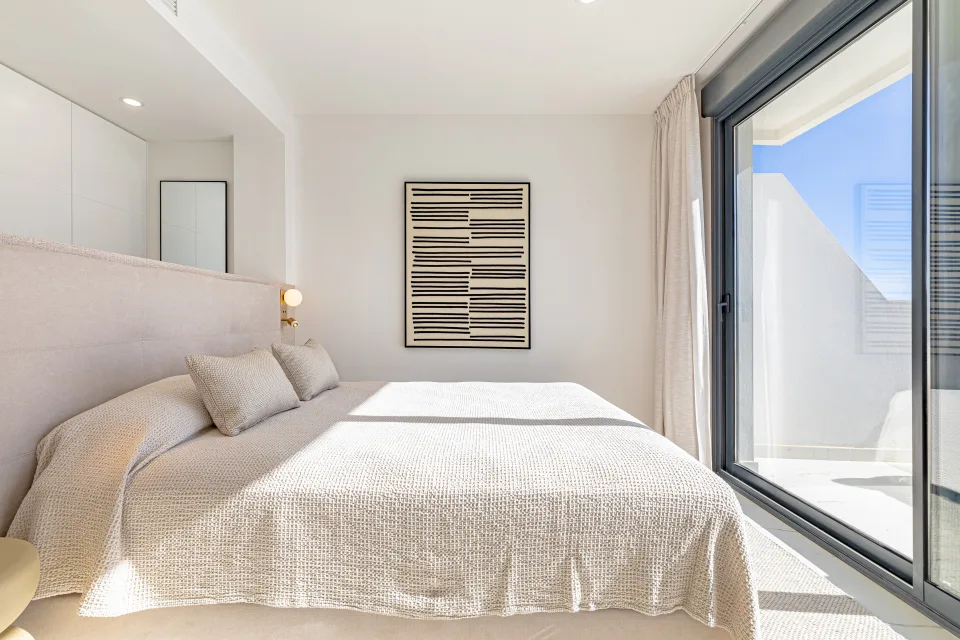 Fotografía de alquiler vacacional de un dormitorio luminoso con cama amplia, decoración minimalista y acceso a terraza privada en Casares Costa