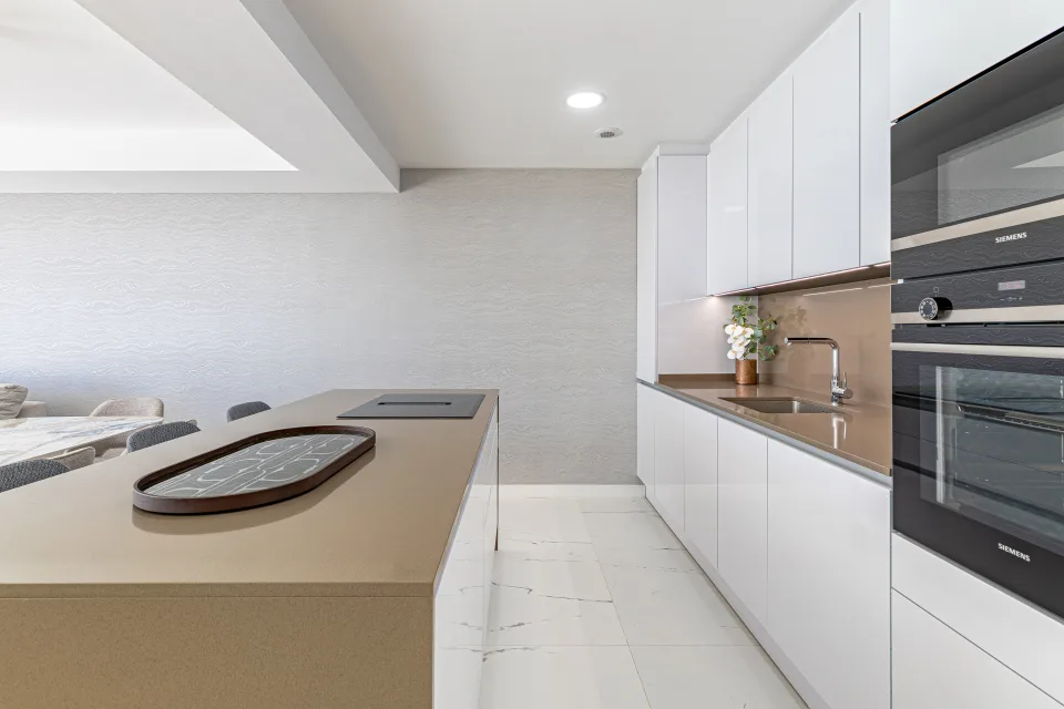 Vacation rental photograph of a modern and bright apartment with an open kitchen, white cabinetry and beige countertop in Casares Costa