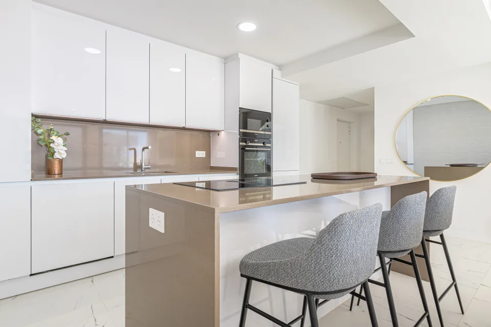 Vacation rental photograph of a modern kitchen with white finishes, breakfast bar and integrated appliances in Casares Costa