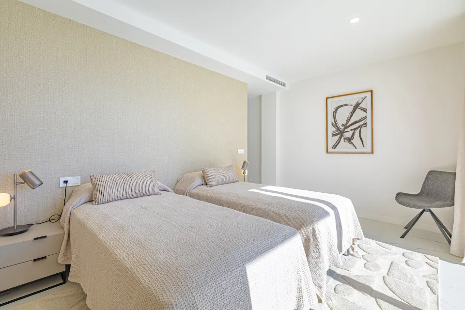 Vacation rental photograph of a bright bedroom featuring two single beds, bedside lamps and minimalist decor in Casares Costa