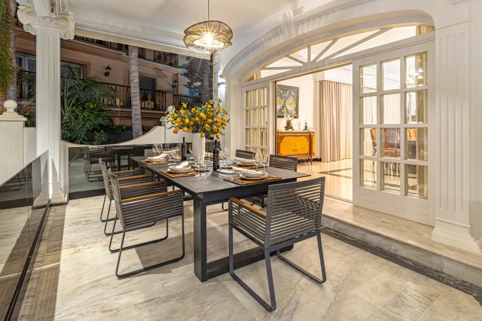 Fotografía de alquiler vacacional de un elegante comedor al aire libre con mesa moderna y sillas, decorado con flores en Marbella