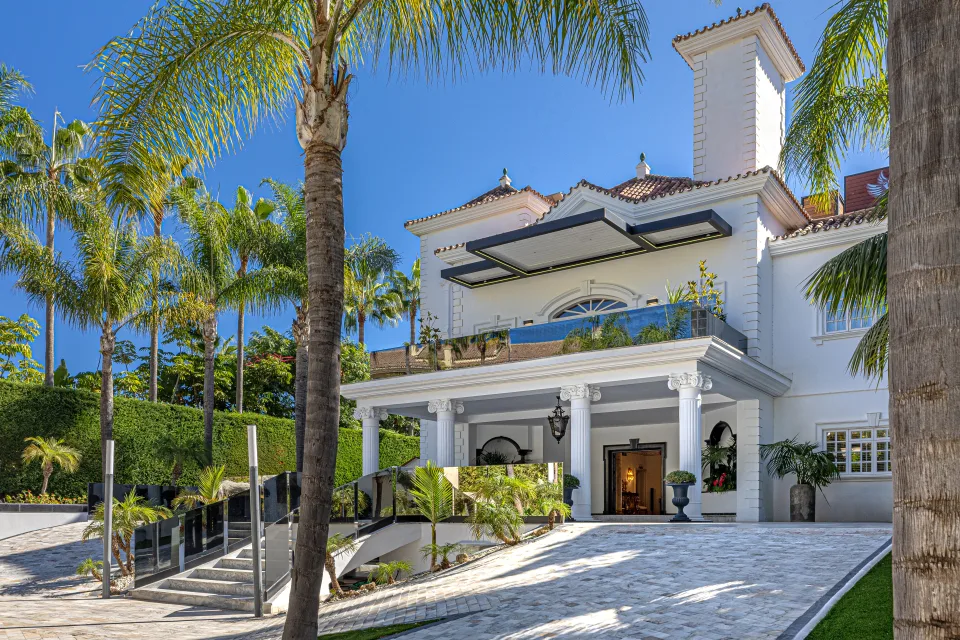 Fotografía de alquiler vacacional de una villa de estilo clásico con elegantes columnas, jardín tropical y piscina en Marbella