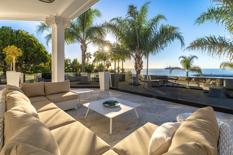 Fotografía de alquiler vacacional de un acogedor salón exterior con sofá de esquina, mesas bajas y vistas al mar en Marbella