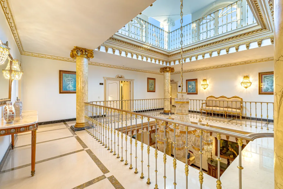 Fotografía de alquiler vacacional de un amplio vestíbulo con columnas doradas, lámparas elegantes y escaleras de mármol en Marbella