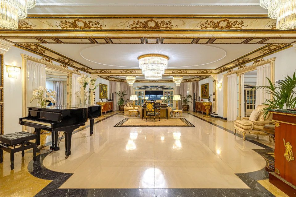 Fotografía de alquiler vacacional de un elegante salón con piano negro, candelabros brillantes y muebles dorados en Marbella