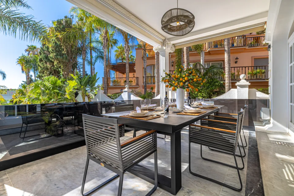Fotografía de alquiler vacacional de un elegante comedor exterior rodeado de palmeras y vegetación en Marbella