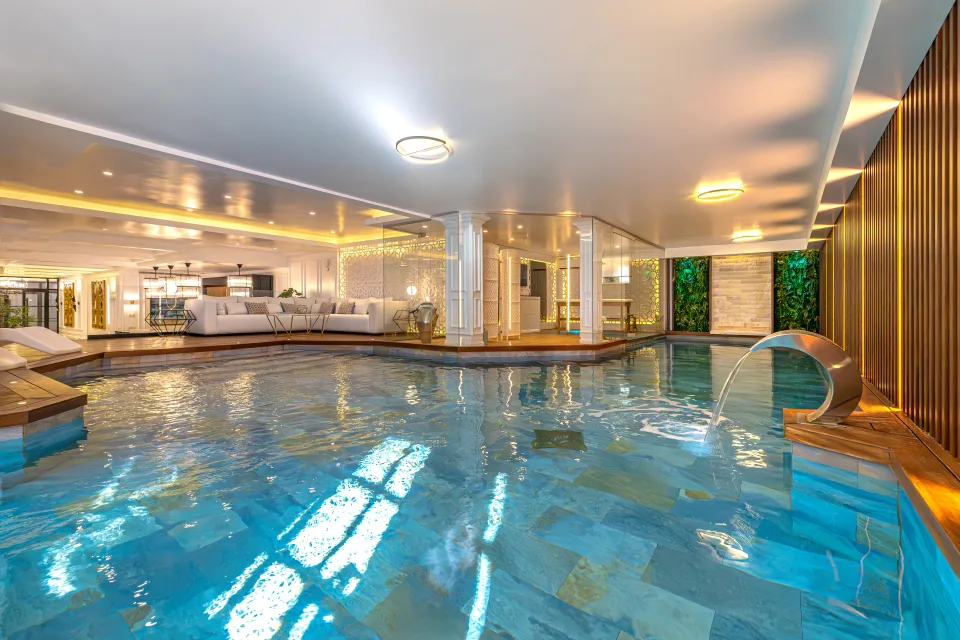 Fotografía de alquiler vacacional de una piscina interior con aguas cristalinas, rodeada de áreas de descanso y detalles en madera en Marbella