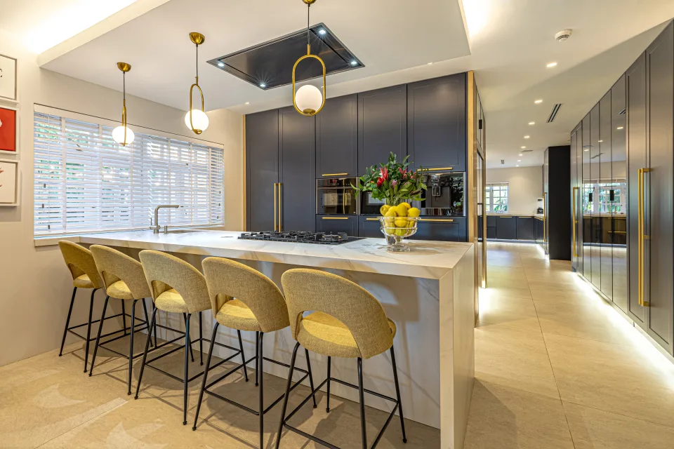 Fotografía de alquiler vacacional de una moderna cocina con isla central, electrodomésticos de acero inoxidable y iluminación cálida en Marbella