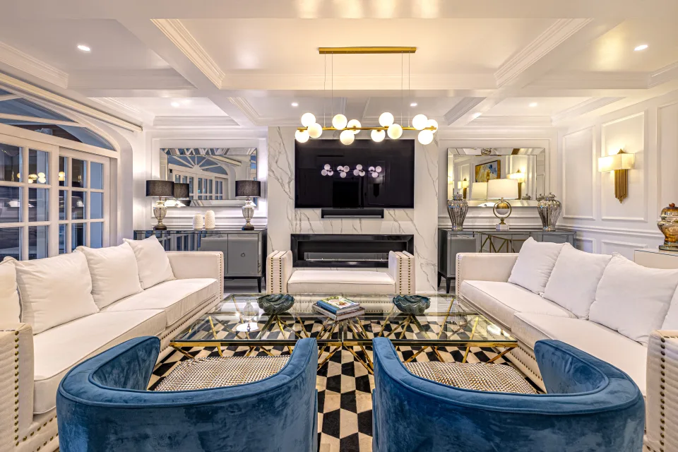 Fotografía de alquiler vacacional de un elegante salón con sofás claros, lámparas de mesa y chimenea moderna en Marbella