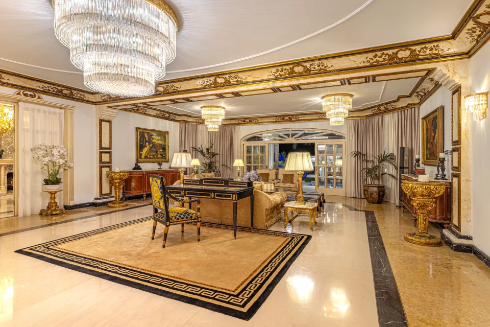 Fotografía de alquiler vacacional de un elegante salón con luminarias de cristal, mobiliario dorado y detalles ornamentales en Marbella