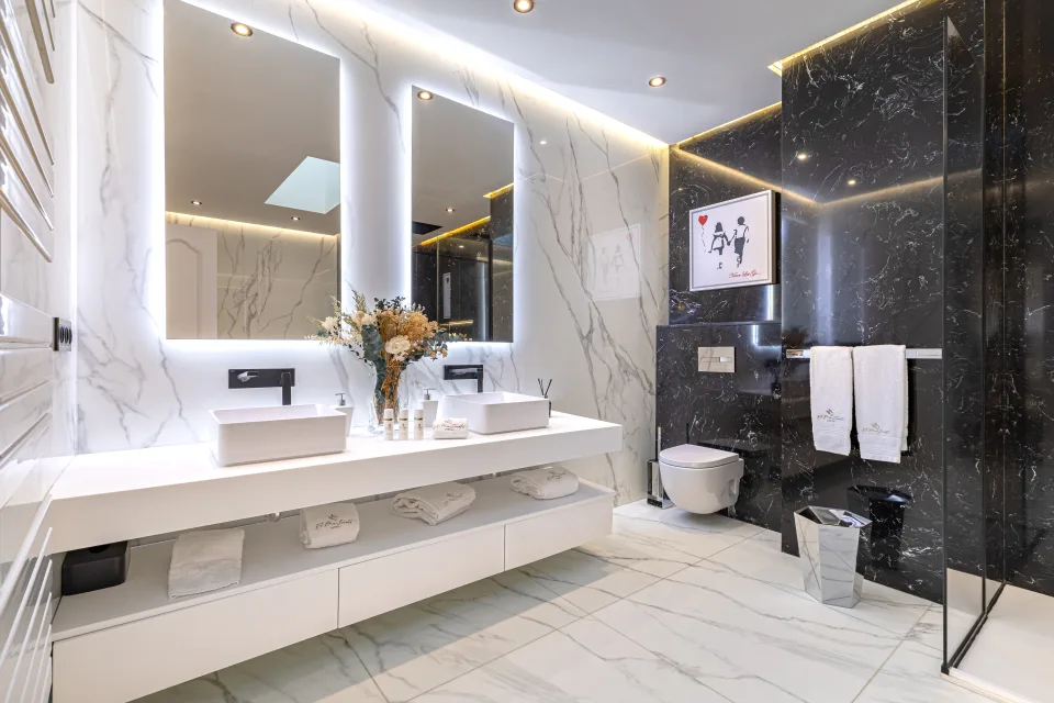 Fotografía de alquiler vacacional de un elegante baño moderno con grifería de acero inoxidable, dos lavabos y ducha a ras de suelo en Marbella