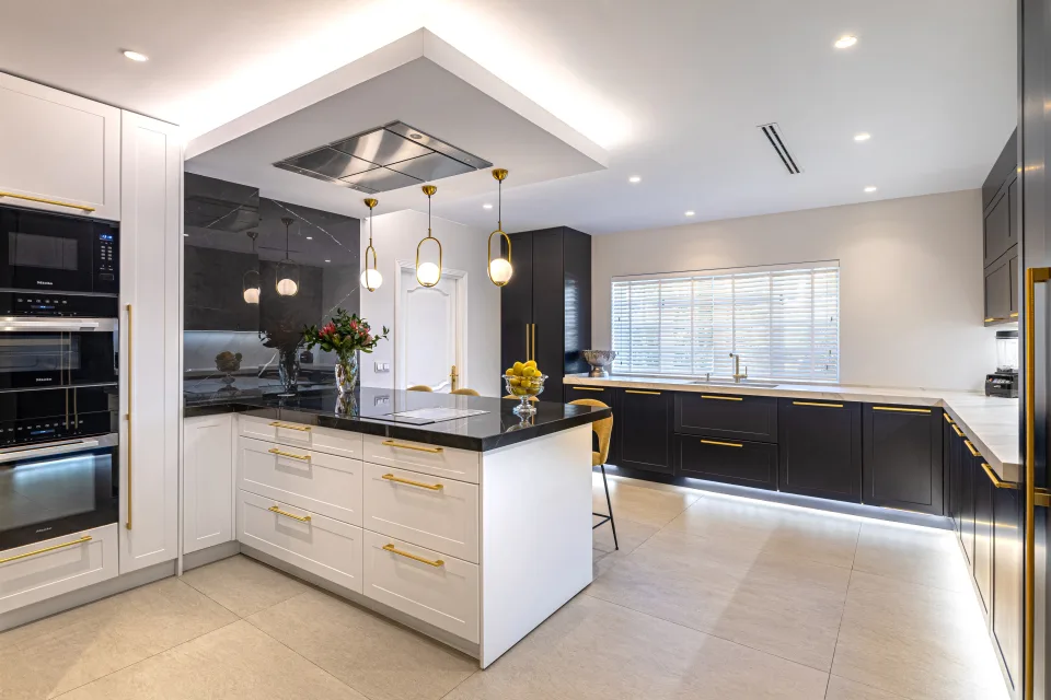 Fotografía de alquiler vacacional de una moderna cocina con islas centrales, armarios oscuros y accesorios dorados en Marbella