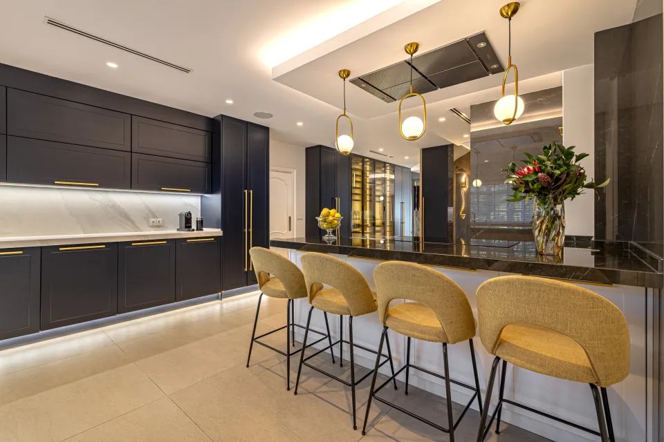 Fotografía de alquiler vacacional de una moderna cocina con muebles oscuros, barra de desayuno y iluminación elegante en Marbella