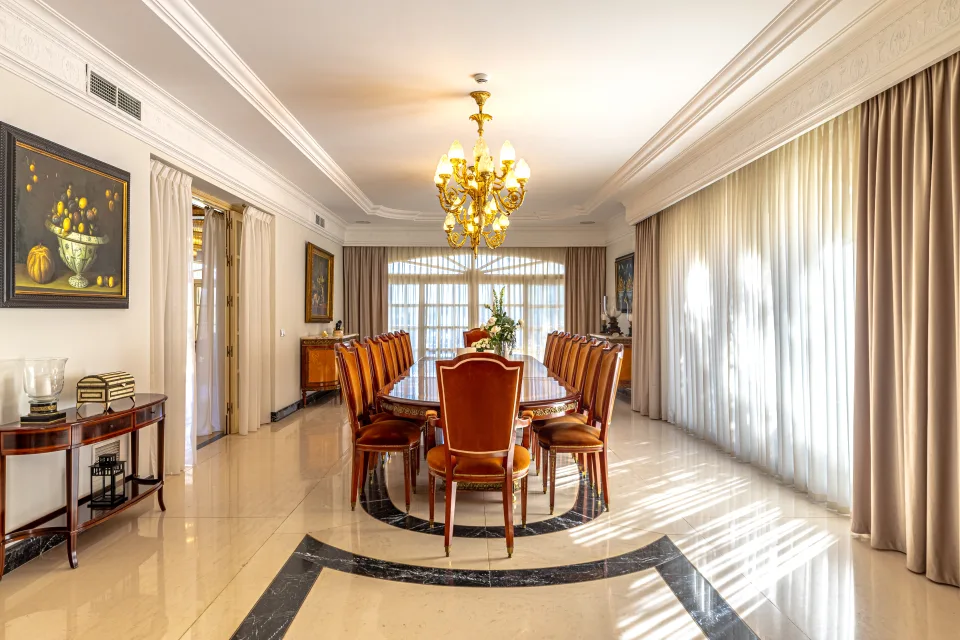 Fotografía de alquiler vacacional de un elegante comedor con mesa larga, sillas de cuero y luz natural en Marbella