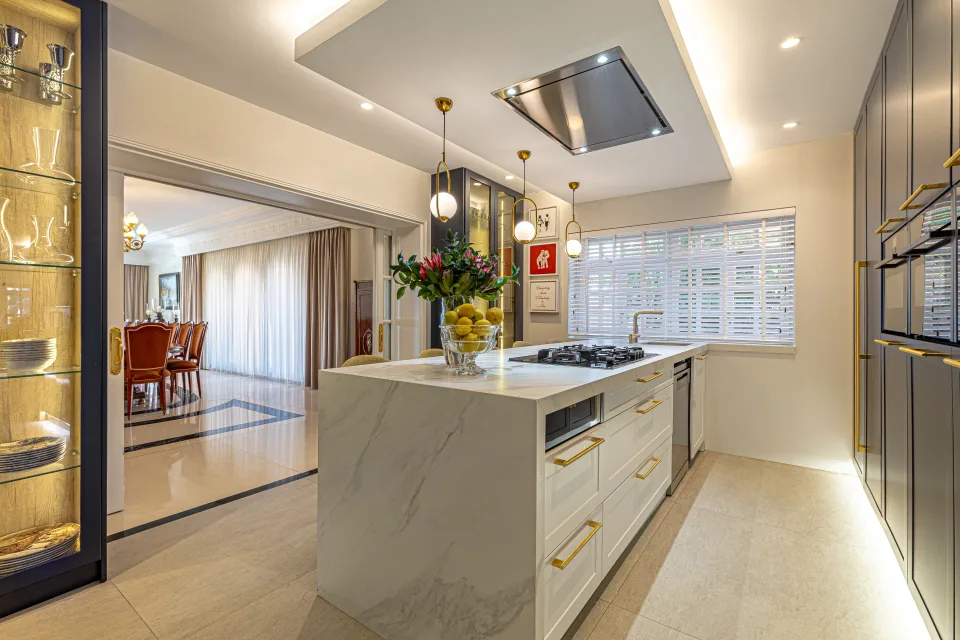 Fotografía de alquiler vacacional de una cocina moderna con isla central, muebles oscuros y detalles dorados en Marbella