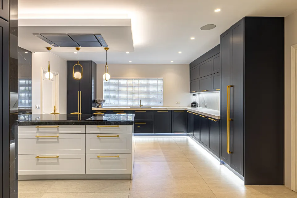 Fotografía de alquiler vacacional de una cocina moderna con mobiliario negro y blanco, iluminación LED y encimera de granito en Marbella