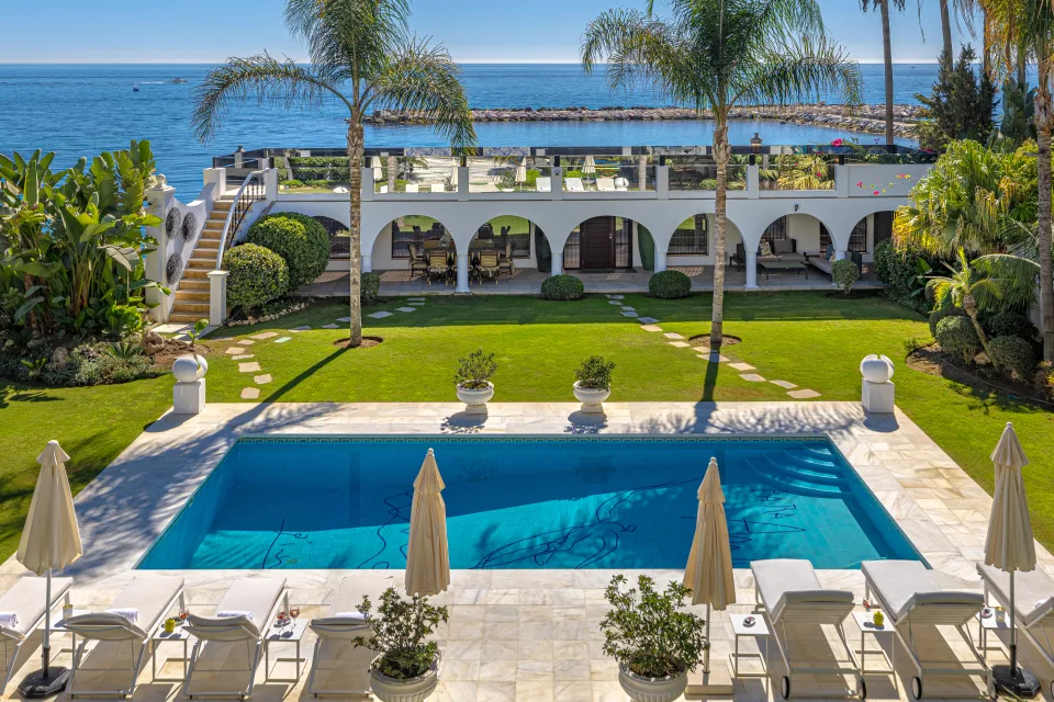 Fotografía de alquiler vacacional de un jardín con piscina, palmeras y vistas al mar en Marbella