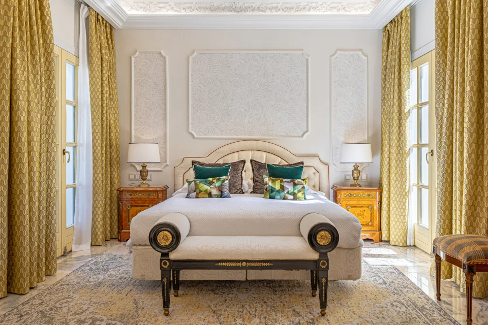 Fotografía de alquiler vacacional de un dormitorio elegante con cama grande, lámparas de mesa y cortinas doradas en Marbella