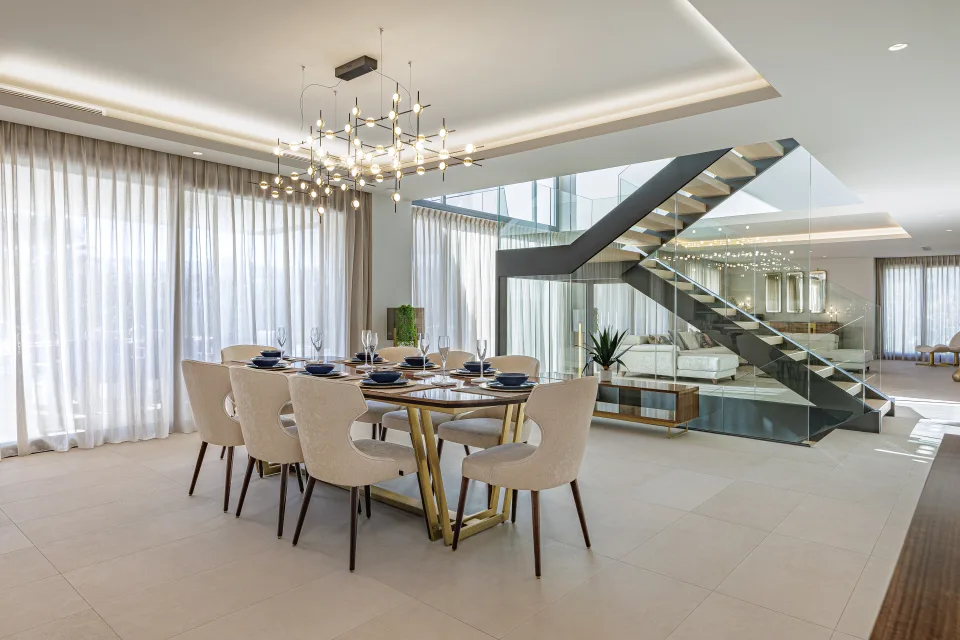 Fotografía de interiorismo y arquitectura de un comedor con mesa de madera dorada, sillas tapizadas en beige en Estepona