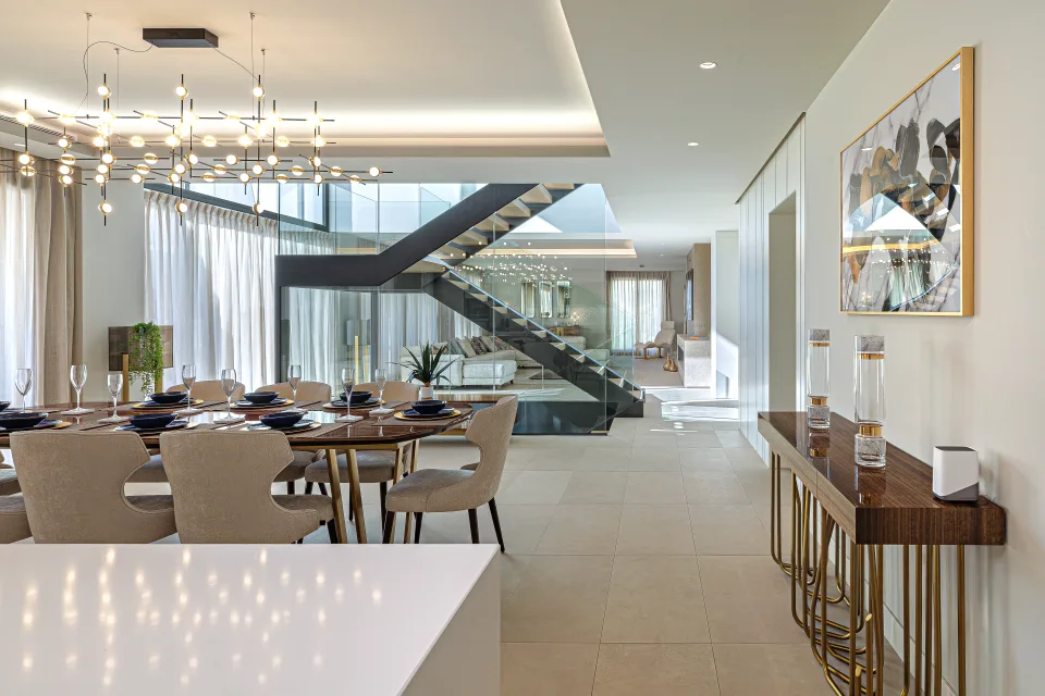Fotografía de interiorismo y arquitectura de un elegante comedor con mesa de madera, sillas tapizadas y una lámpara de diseño en Estepona