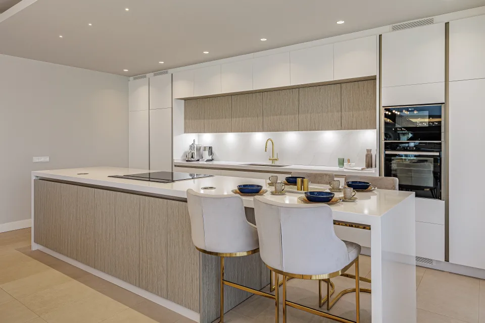 Fotografía de interiorismo y arquitectura de una elegante cocina con muebles en tonos claros, isleta central en Estepona