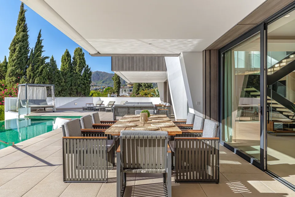 Fotografía de interiorismo y arquitectura de un elegante comedor al aire libre con mesa de madera y sillas modernas en Estepona