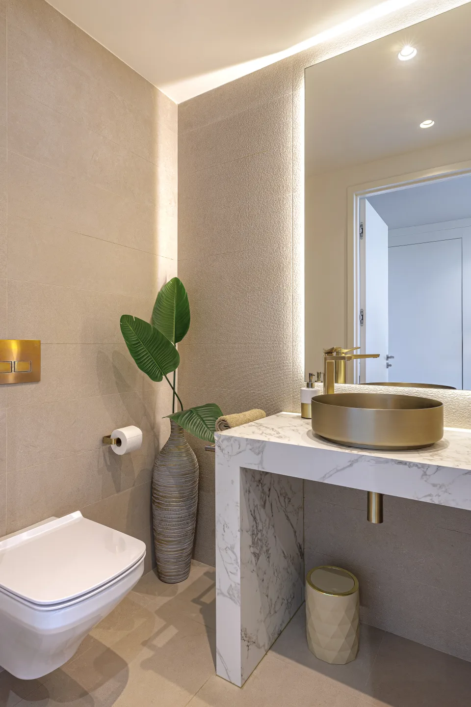 Fotografía de interiorismo y arquitectura de un elegante baño con lavabo de mármol, grifería dorada y decoración con plantas en Estepona | Villa de 4M€ en El Paraíso