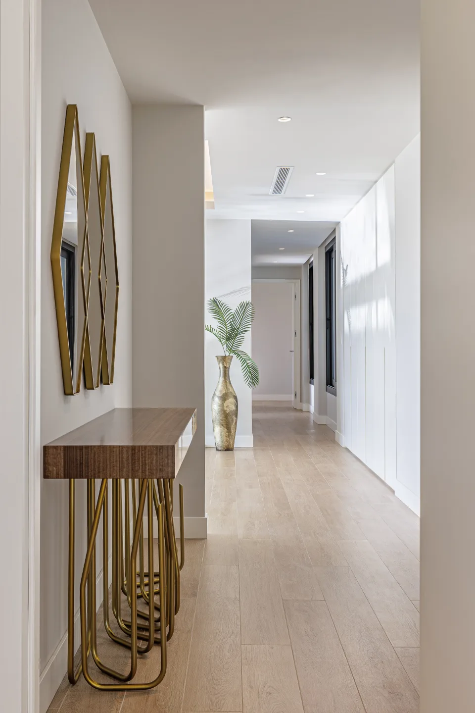 Fotografía de interiorismo y arquitectura de un pasillo luminoso con mesa de consola de madera y espejos dorados en Estepona | Villa de 4M€ en El Paraíso