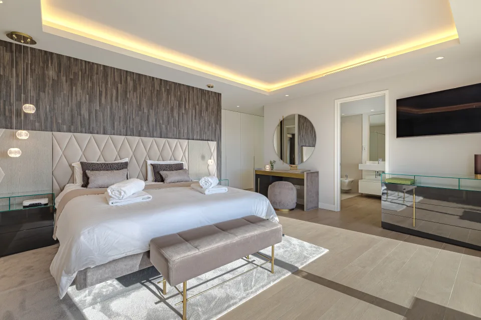 Fotografía de interiorismo y arquitectura de un elegante dormitorio con cama king size, iluminación cálida y mobiliario contemporáneo en Estepona