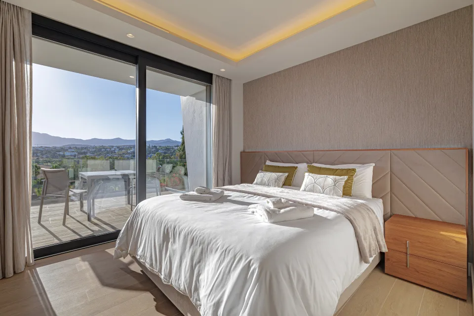 Fotografía de interiorismo y arquitectura de un dormitorio luminoso con cama amplia, cabecero tapizado en Estepona