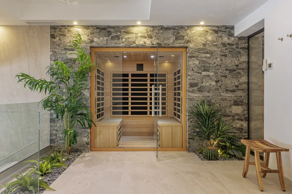 Fotografía de interiorismo y arquitectura de una sauna de madera con paredes de piedra y vegetación decorativa en Estepona