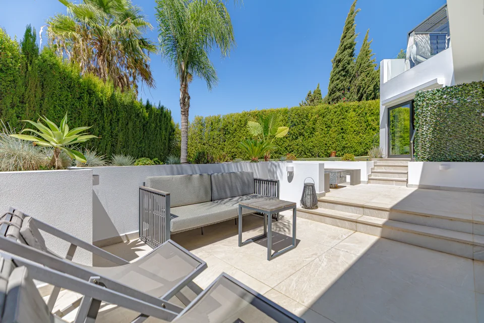 Fotografía de interiorismo y arquitectura de un patio con cómodos sillones, mesa de café y abundante vegetación en Estepona