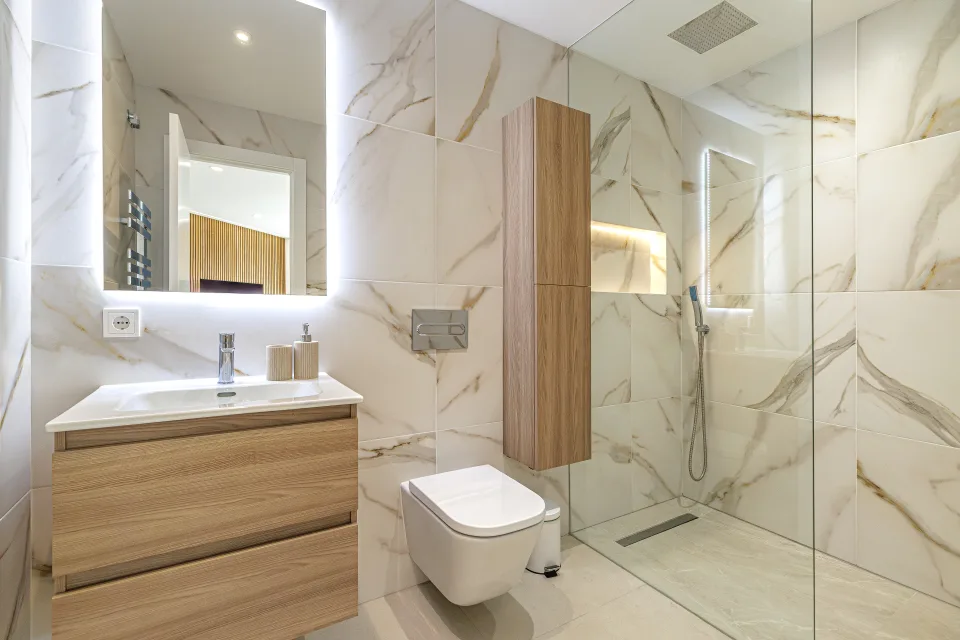 Fotografía de interiorismo y arquitectura de un baño moderno con alicatado en tonos claros, mueble de lavabo en madera en Estepona