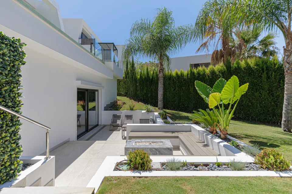 Fotografía de interiorismo y arquitectura de un exterior con jardín bien cuidado, piscina y mobiliario moderno en un ambiente soleado en Estepona