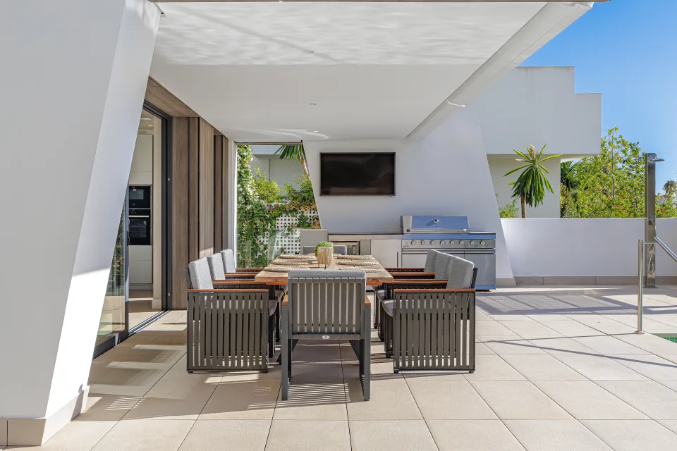 Interior design and architecture photograph of a modern outdoor space featuring a large dining table, comfortable chairs in Estepona