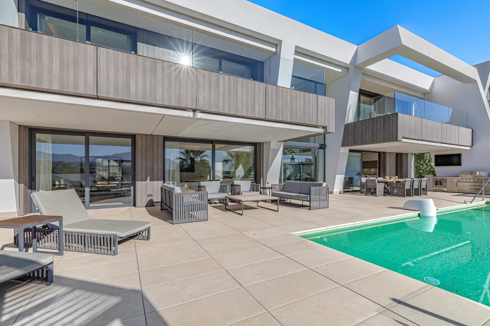 Interior design and architecture photograph of a stylish outdoor patio with swimming pool, modern furniture and sun lounging areas in Estepona