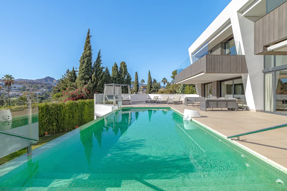 Interior design and architecture photograph of an infinity pool surrounded by gardens and modern outdoor furniture in Estepona