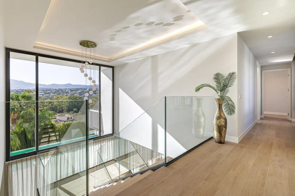 Interior design and architecture photograph of a bright hallway with glass stairs and views of the landscape in Estepona
