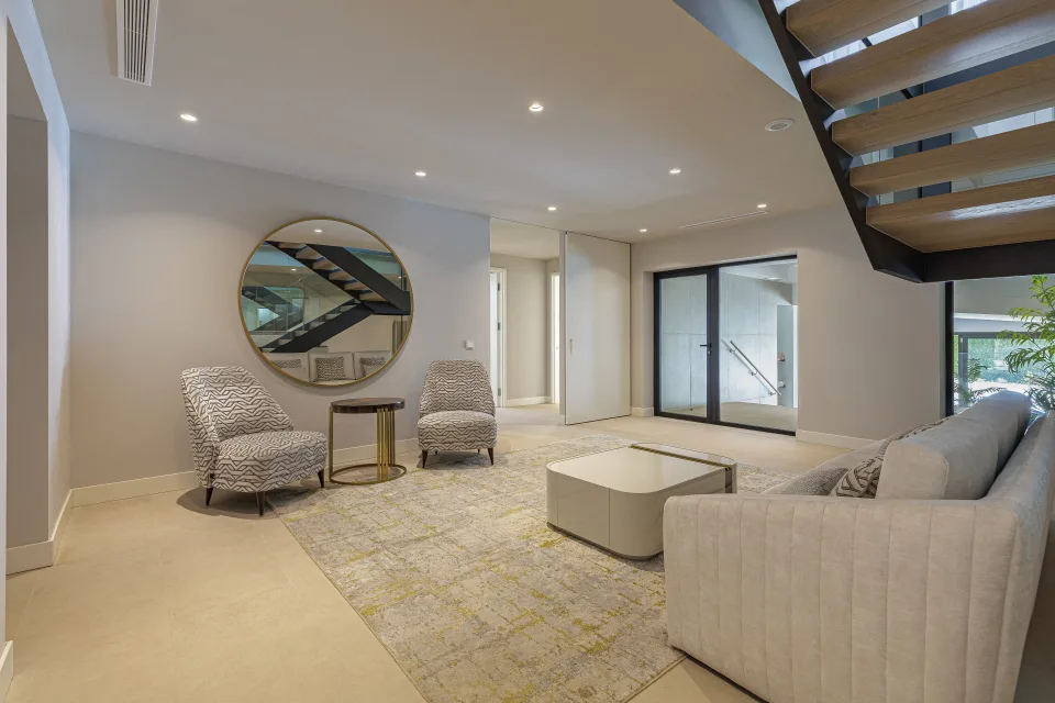 Interior design and architecture photograph of a stylish living room with light armchairs, round table and large windows in Estepona