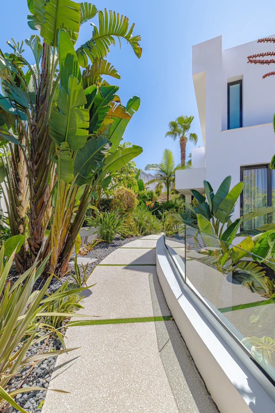Interior design and architecture photograph of a pathway surrounded by lush tropical gardens, varied vegetation in Estepona | 4M€ Villa in El Paraíso