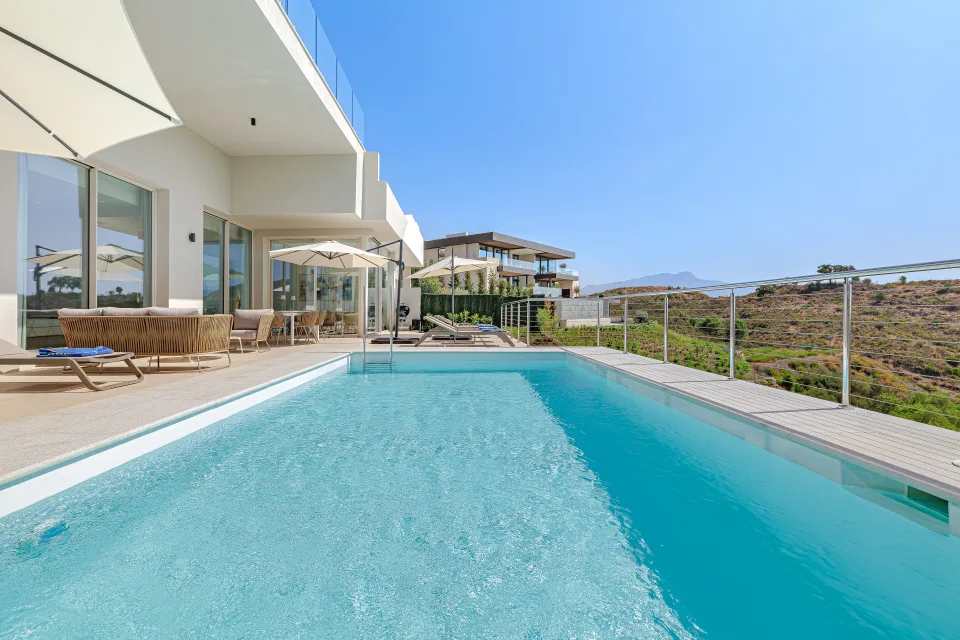 Vacation rental photograph of a modern pool with sun loungers and clear views of the landscape in Benahavís