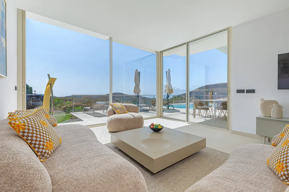 Vacation rental photograph of a bright living room with large windows, modern furnishings and outdoor views in Benahavís